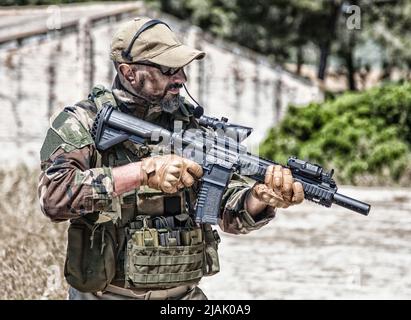 Private military company mercenary in battle uniform, holding service rifle in hands, ready to fight. Stock Photo