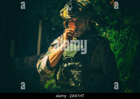 Army soldier smoking cigarette at night. Stock Photo