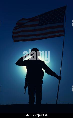 Silhouette of a saluting U.S. soldier holding national flag against the moonlit night sky. Stock Photo