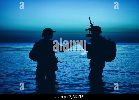 Silhouette of soldiers celebrating with fist bump gestures while ...