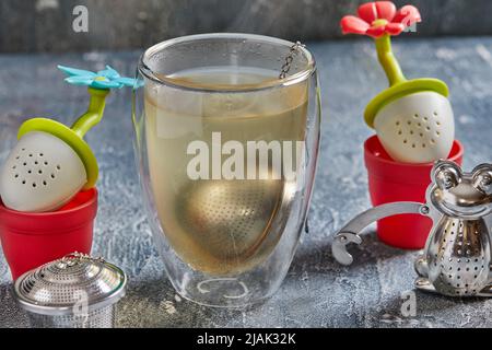 Tea brewing tools in the form of frogs and flowers with glass of tea Stock Photo