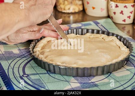 Chef makes stripes on the pie dough with knife before baking in the oven Stock Photo