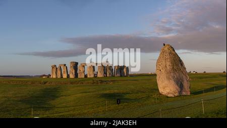 The Heel stone with bird perched at the historical landmark of Stonehenge in the background panorama shot Stock Photo