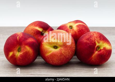 Ripe red peaches isolated on wooden table Stock Photo