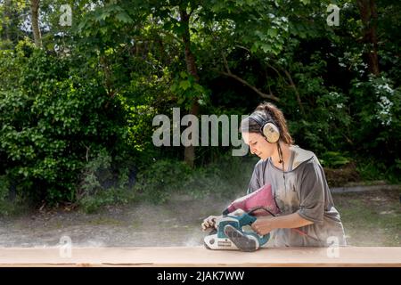 Bantry, Cork, Ireland. 30th May, 2022. Woodworker Britta Faller sanding down a plank of Douglas-Fir that will be made into a table at the Beantree workshop outside Bantry, Co. Cork, Ireland.  - Credit; David Creedon / Alamy Live News Stock Photo