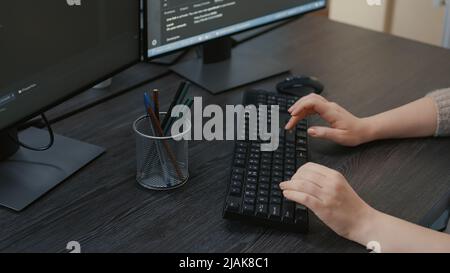 Closeup of caucasian programer hands typing machine learning code on keyboard in front of computer screens with programming interface. System engineer sitting at desk writing algorithm for it agency. Stock Photo