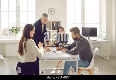Group of positive people discuss plan for cooperation on common project in modern coworking. Stock Photo