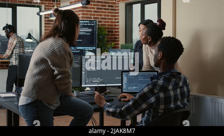 Software developers discussing about cloud programming innovation while the rest of the team joins the discussion. Programmers doing teamwork computing big data in server room. Stock Photo