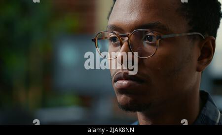 Portrait of software developer with glasses reading ai algorithm working focused looking at computer screen. Focus on moving eyes of software developer writing database code in front of monitor. Stock Photo