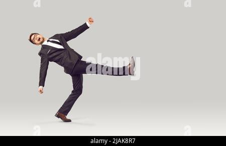 Strange funny crazy businessman in suit walking against light gray studio background Stock Photo