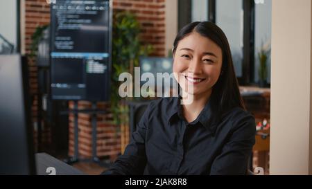 Smiling software developer typing machine learning app code on computer keyboard sitting at desk in big data office. Friendly cloud programer working casually in cyber security agency. Stock Photo