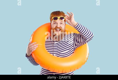 Funny fat man with lifebuoy around his neck, waist and sunglasses isolated on light blue background. Stock Photo