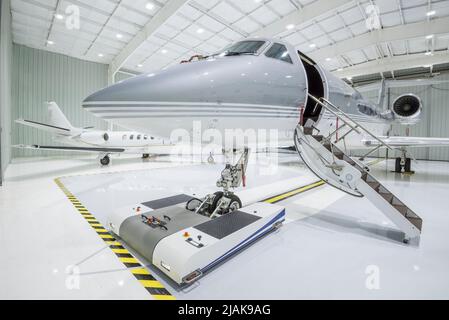 Two small private Jet airplanes parked in a hangar - stock photo Stock Photo