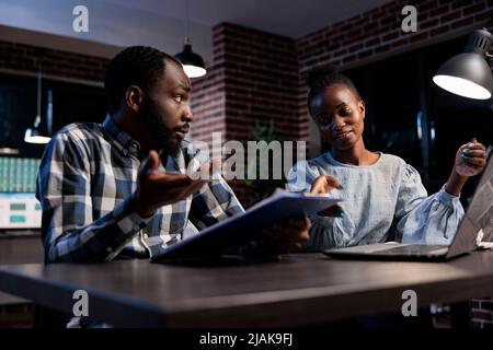 Financial analysts in office workspace discussing about investors capital and profits growth. Hedge fund company professional employees working together to predict stock market trend. Stock Photo