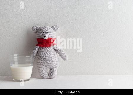rochet knitting cute teddy bear with a glass of milk on a white table Stock Photo