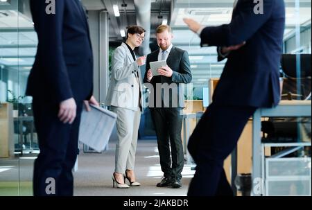 Two busness partners using tablet pc to watch online presentation and discussing it during teamwork at office Stock Photo