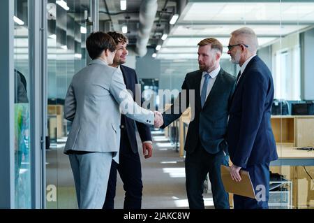 Group of business people in formal wear greeting each other while having meeting at office Stock Photo