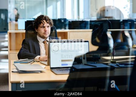Business people working on laptops at table behind glass wall at office Stock Photo