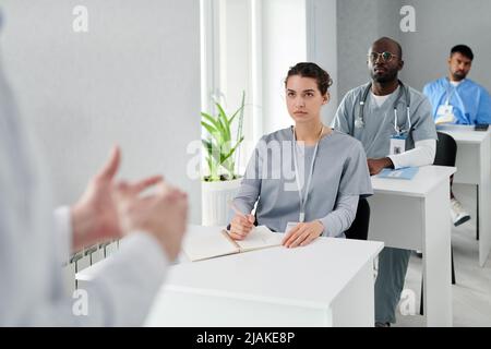 Group of physicians sitting at desk and listening to speaker during medical training at class Stock Photo