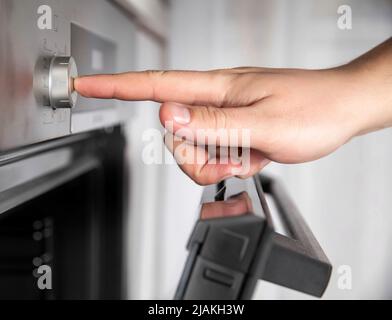 Modern oven with recessed function controls. Man's hand presses a recessed regulator Stock Photo