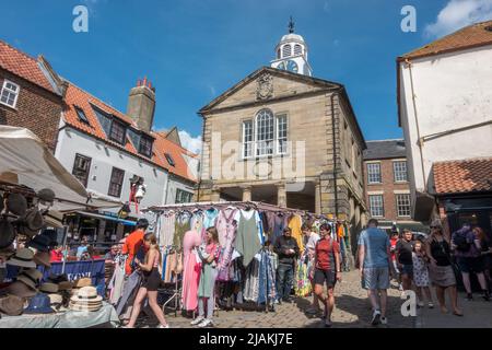 Market stalls in Market Square with the old Clock Tower, Church Street in Whitby, North Yorkshire, UK. Stock Photo