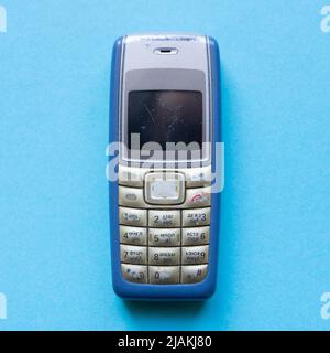 Old blue button mobile phone on blue background Stock Photo