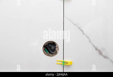 A hole in the wall with a tile for an outlet. Marble leveling system Stock Photo