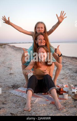 happy fun family resting on the shore. mom and daughters at a picnic Stock Photo