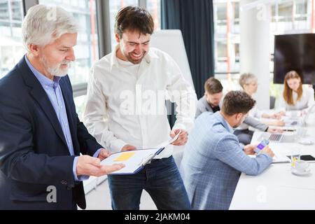 Senior manager and young businessman in the office review a checklist together Stock Photo