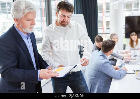 Senior boss and business man checking checklist on clipboard together in office Stock Photo