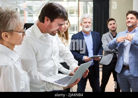 Programmer using laptop computer in software development with team in background Stock Photo