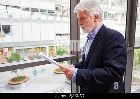 Experienced businessman as a consultant or manager reads and checks documents in the office Stock Photo