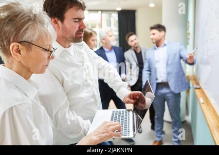 Business people doing research on laptop PC with team at brainstorming workshop Stock Photo