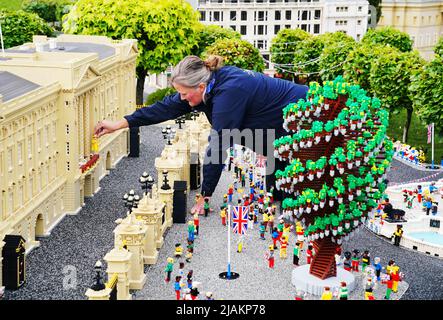 Model Maker Paula Young places a LEGO replica of Queen Elizabeth II, along with other members of the Royal Family, in a display replicating the Royal Balcony scene at Buckingham Palace for the LEGOLAND Resort's Platinum Jubilee Display that was unveiled today. All members of the Royal family took 8 hours to build and are made up of over 200 LEGO Bricks. LEGOLAND Windsor Resort today unveiled its royal-inspired models to celebrate the Queen's Platinum Jubilee. The overall number of bricks used was 18,001 and the models took a total of 281.5 hours to finish. The display also includes includes a  Stock Photo