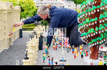 Model Maker Paula Young places a LEGO replica of Queen Elizabeth II, along with other members of the Royal Family, in a display replicating the Royal Balcony scene at Buckingham Palace for the LEGOLAND Resort's Platinum Jubilee Display that was unveiled today. All members of the Royal family took 8 hours to build and are made up of over 200 LEGO Bricks. LEGOLAND Windsor Resort today unveiled its royal-inspired models to celebrate the Queen's Platinum Jubilee. The overall number of bricks used was 18,001 and the models took a total of 281.5 hours to finish. The display also includes includes a  Stock Photo