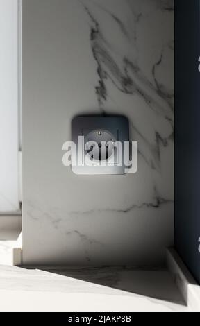Silver EU power socket on white marble wall Stock Photo