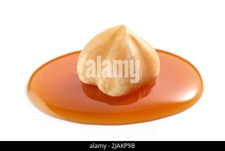 hazelnut in drop of melted caramel sauce isolated on white background Stock Photo