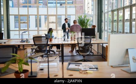 Diverse group of young businesspeople talking over coffee in an office Stock Photo