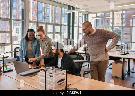 Diverse group of focused businesspeople working together on a laptop Stock Photo