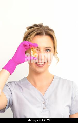 The master of sugar hair removal holds liquid yellow sugar paste