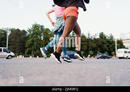 Side view of friends legs in sportswear running in the city. Multiethnic women having a fitness workout. Stock Photo