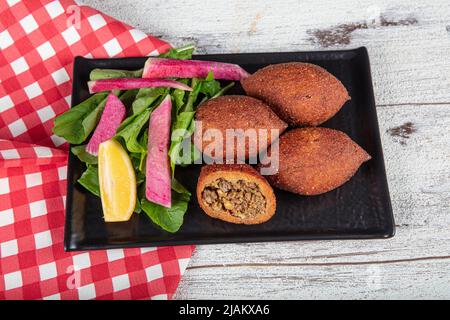 Kibbeh on a white wood background. Kibbeh is a popular dish in Middle Eastern cuisine. Stuffed Meatballs Food, Falafel, icli Kofta, Quibe. Top view. E Stock Photo