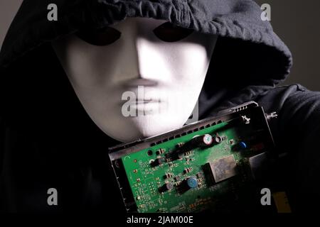 electronic circuit board with processor in the hands of a masked man Stock Photo