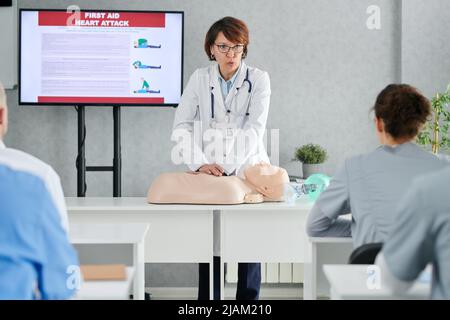 Medical specialist demonstrating on mannequin how to providing first aid to students at training Stock Photo