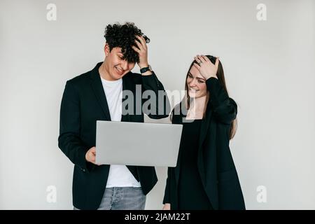 Two puzzled, surprised and shocked woman and man standing with laptop, looking at screen. Troubles in work, unbelievable Stock Photo
