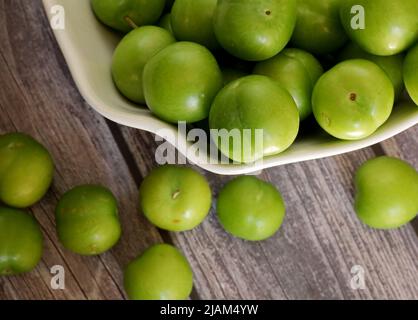 green plums on the wooden table Stock Photo