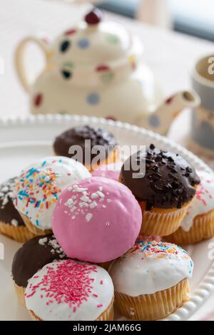 Colourful cupcakes on plate at teatime Stock Photo