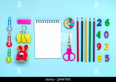 Frame from school and office supplies Paper clips, pens, felt-tip pens, sharpener, notepad, stapler isolated on blue background Flat lay Top view Back Stock Photo