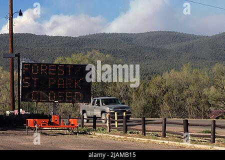 Sign advising closure of the Santa Fe Nstional Forest in the town of Pecos New Mexico on May 14, 2022. Smoke from the nearby  Calf Canyon/Hermits Peak forest fire fills the sky. The Hermits Peak forest fire starteed on April 6, 2022 after multiple spot fires spreadfrom a perscribed fire project. On April 22 the Hermits Peak fire merged with the Calf Canyon fire which started on April 19. The two fires are now being treated as one and have burned 288,942 acres as of May 15. It is the largest wildfire currently burning in the United States. [SipaUSA] (Photo by Steve Clevenger/Sipa USA) Stock Photo