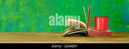 Open book, vintage hardback book and cup of coffee on green  background. Education, reading, research concept. Stock Photo